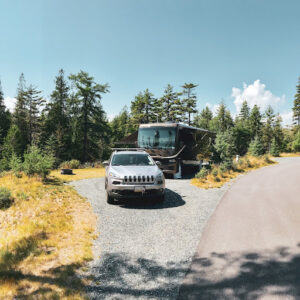 Jeep and Class A RV parked in nature