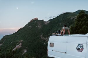 a couple on the rooftop of a van watching the moon and mountain environment