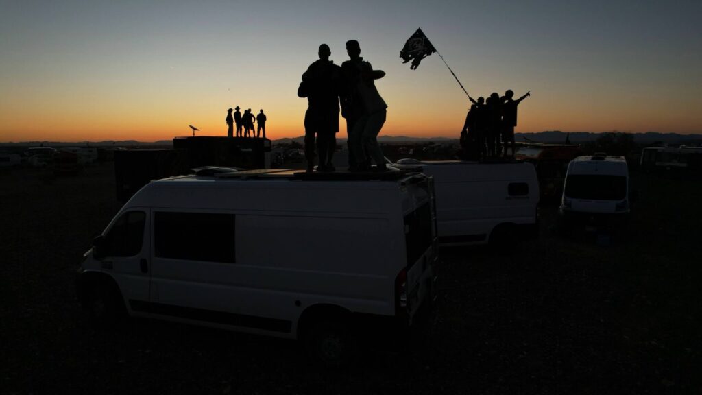 three vans with people on the roofdeck during sunset