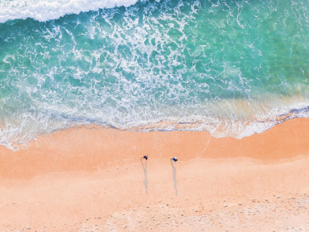 Two people on empty beach during off-season travel