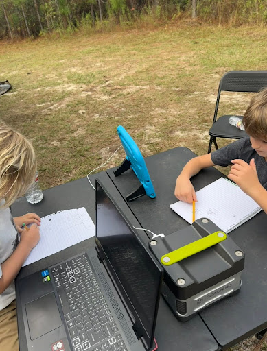 two kids studying outside with laptops and solar generators
