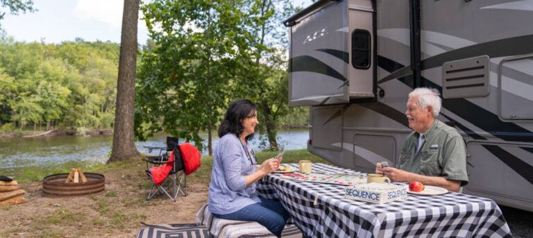 An older couple playing cards next to their RV